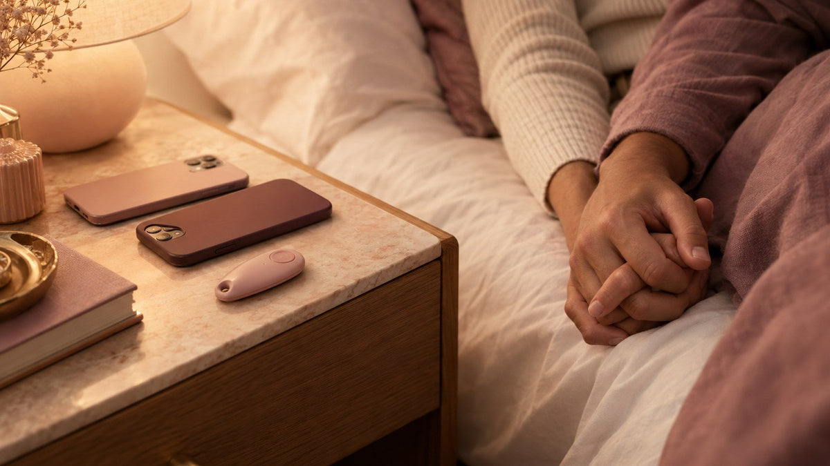 Two smartphones and a small blush remote fob on a nightstand