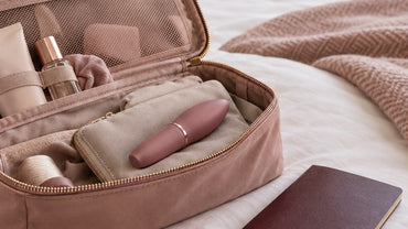 An open travel toiletry bag with a small smooth lipstick-shaped device