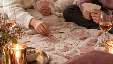 A couple's hands playing a card game on a cozy blanket