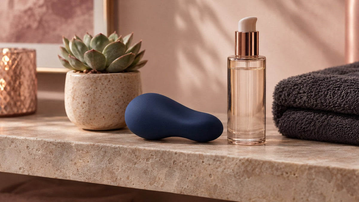 A smooth abstract curved pebble-shaped navy silicone wellness object beside a bottle of lubricant